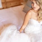 la mariée pose sur le lit en robe blanche